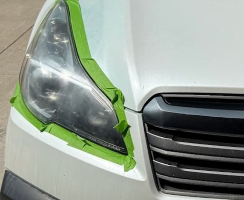 Cleared headlight on a white Subaru, with masking tape still in place