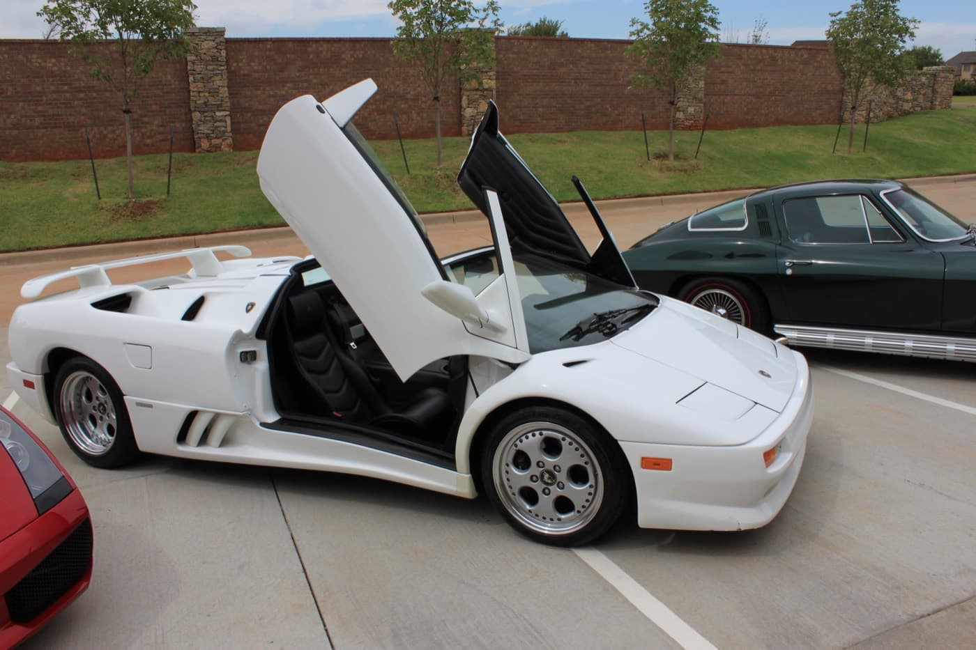 A white Lamborghini Diablo VT Roadster with its scissor doors up after a full exterior detail