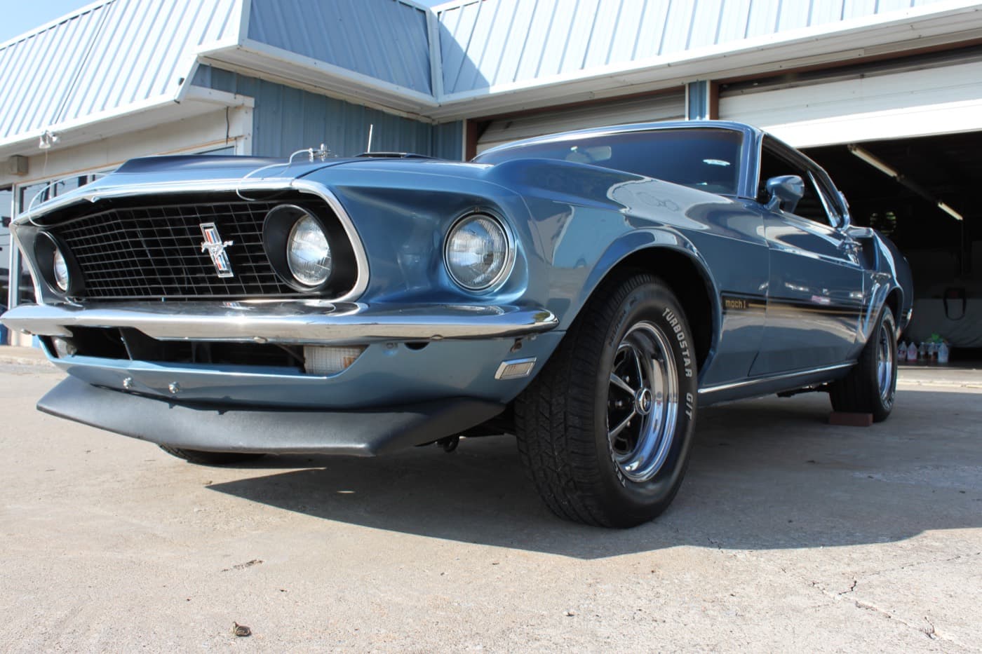 A blue 1969 Mustang Mach 1 fastback shot from a low front angle after a detail